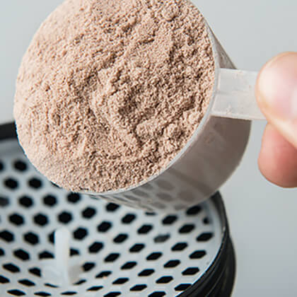 Premier Protein powder being poured into a blender.